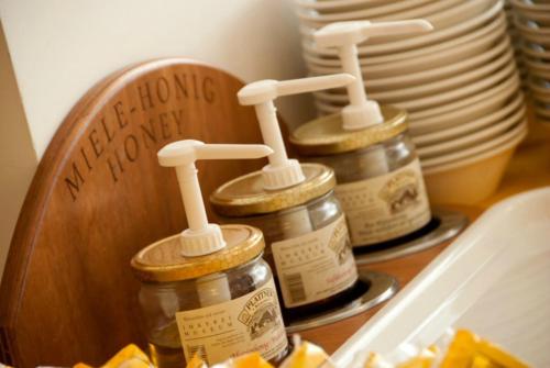 three jars of honey on a table with plates at Hotel Touring in Falconara Marittima