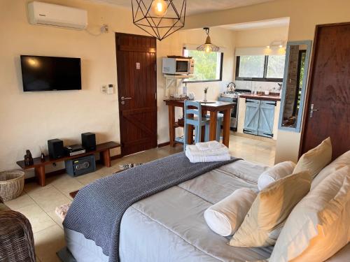 a bedroom with a large bed and a kitchen at Los Pecados de la Viuda in Punta Del Diablo