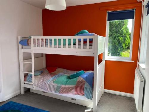 ein weißes Etagenbett in einem Zimmer mit orangefarbener Wand in der Unterkunft Secluded 3 bed cottage in private parkland in Brockenhurst