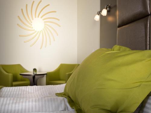 a bedroom with a bed and two green chairs at Boutique Hotel Bellevue Rheinfelden / Basel in Rheinfelden