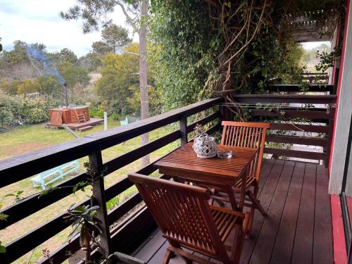 a wooden table and two chairs on a deck at Los Pecados de la Viuda in Punta Del Diablo