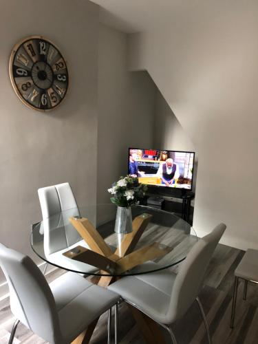 uma sala de jantar com uma mesa de vidro e um relógio em 2 Bedroom Luton Townhouse em Luton