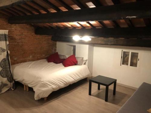 Un dormitorio con una cama blanca con almohadas rojas y una mesa. en Charming house next to the sea and Barcelona for 6 en Badalona