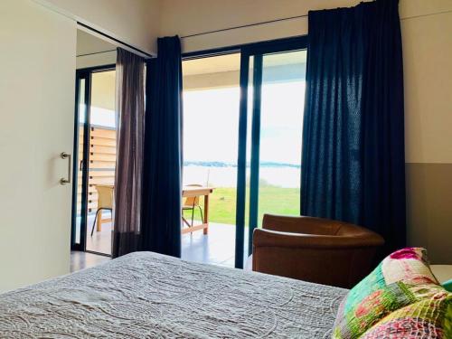 una camera con letto, sedia e porte scorrevoli in vetro di Villa General Belgrano Lago Los Molinos a Potrero de Garay