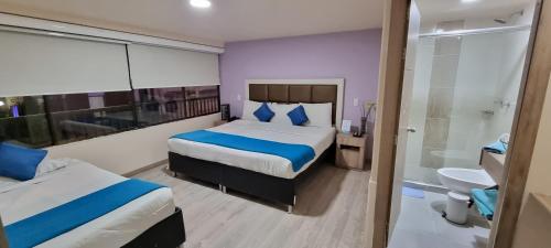 a hotel room with two beds and a bathroom at Blue House Corferias in Bogotá