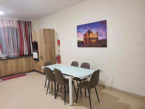 een tafel en stoelen in een kamer met een foto aan de muur bij B&S Accommodation Solitary Duplex Maisonette in Żejtun