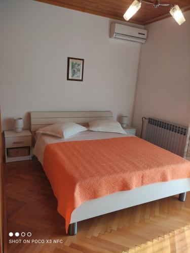 a bedroom with a bed with an orange comforter at Villa Radić in Makarska