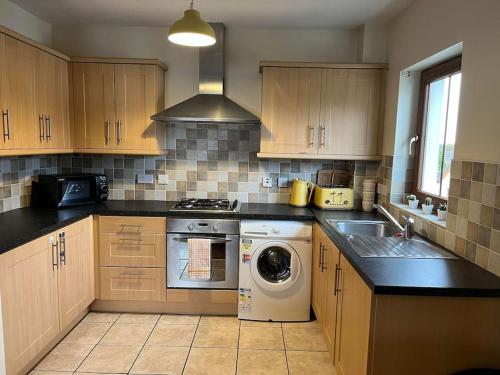 a kitchen with a stove and a washer and sink at Lovely 2 bedroom family apartment in Newcastle in Newcastle