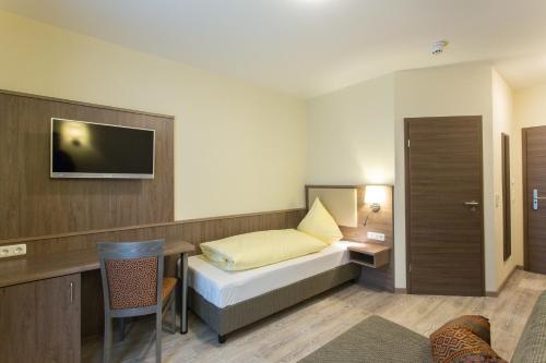 Habitación de hotel con cama, escritorio y TV. en CityApart Hotel, en Dingolfing