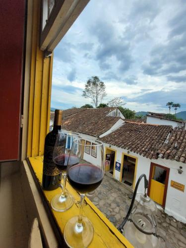 two glasses of wine sitting on a table with a window at Pousada Casa Da Lapa in Paraty