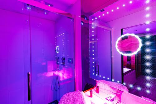 La salle de bains rose est pourvue d'un lavabo et d'un miroir. dans l'établissement GlamappartSpa design luxe & Parking, à Dijon