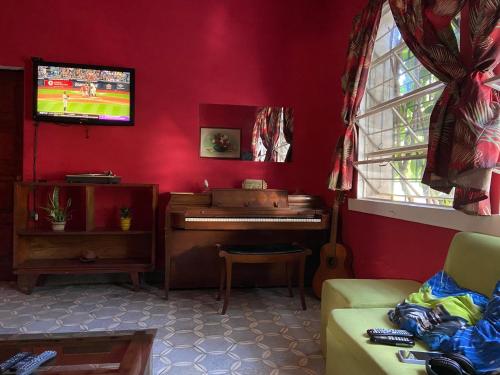 a living room with a piano in a red wall at Hostal Cumbres del Volcan Flor Blanca in San Salvador