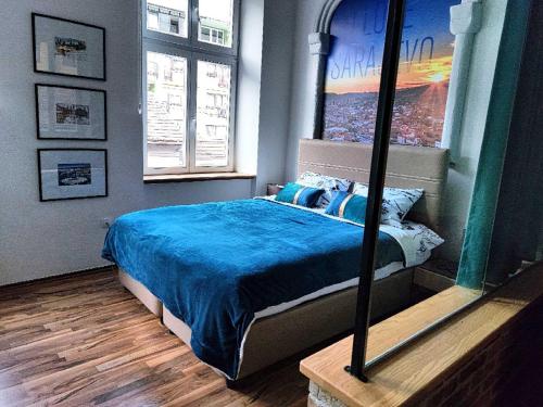 - une chambre avec un lit avec une couette bleue et 2 fenêtres dans l'établissement KIZZ Apartment, à Sarajevo