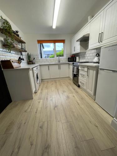 a kitchen with white cabinets and a wooden floor at Elmwood House in Bangor