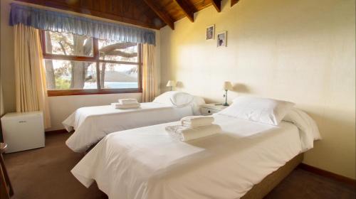 1 dormitorio con 2 camas y ventana en Hosteria Belvedere en Villa La Angostura