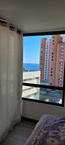 a bedroom with a large window with a view of a building at Edmundo Eluchans plaza 2066 Reñaca in Viña del Mar