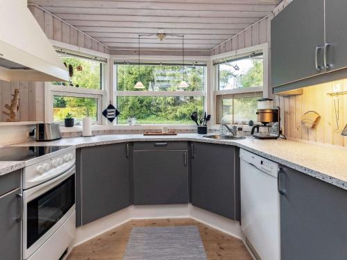 a kitchen with gray cabinets and windows and a counter at 6 person holiday home in Farsø-By Traum in Farsø