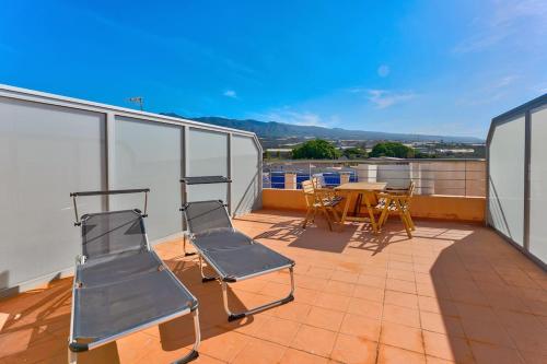 Un balcón con sillas y una mesa en un tejado. en Pleasant Duplex San Juan with 2 bedrooms, en Guía de Isora