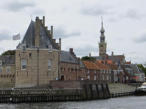a building on the water next to a group of buildings at Boerderijcamping Plantlust in Veere