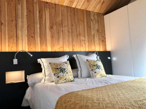 a bedroom with a bed with white sheets and pillows at Cabañas Rias Baixas in Pobra do Caramiñal