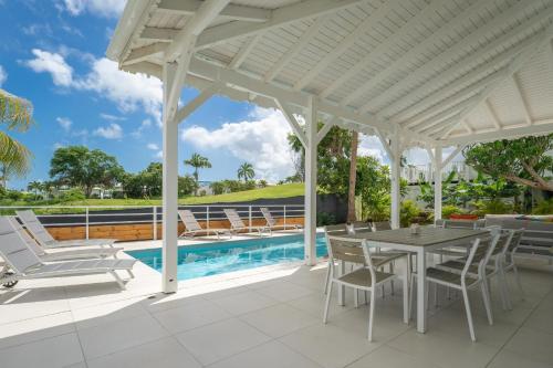 un patio avec une table et des chaises et une piscine dans l'établissement Villa Green Caraibes, à Saint-François