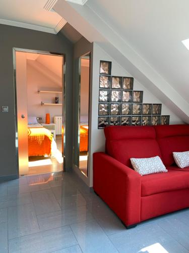 a red couch in a room with a bedroom at Luminoso y centrico apartamento en Plaza de España posición estratégica in Pontevedra