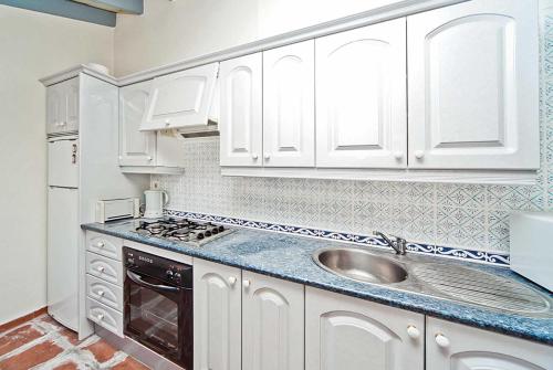 una cocina con armarios blancos y fregadero en Cortijada de Marta, en Fuengirola