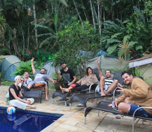 a group of people sitting on chairs by a pool at Hostel Trópico de Capricórnio - Tenório in Ubatuba