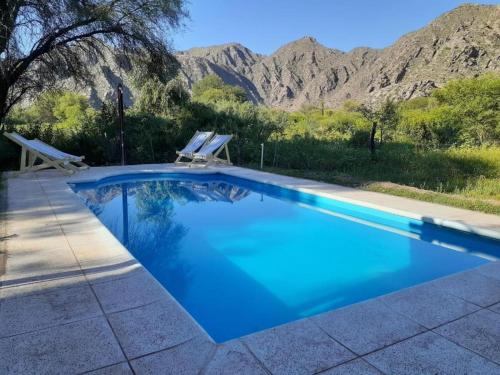 a blue swimming pool with mountains in the background at Hotel Hacienda Casa Blanca in Tinogasta