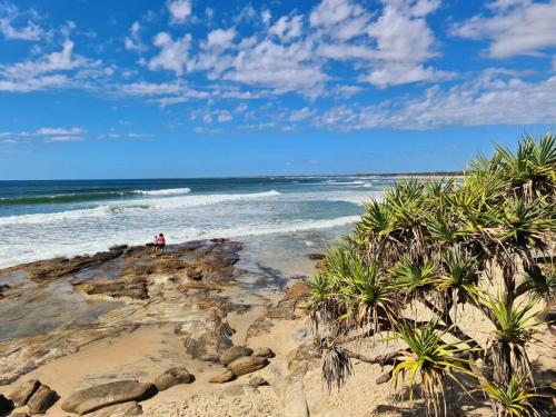 a person standing on a beach near the ocean at Ashwood on Kings- Kings Beach in Caloundra