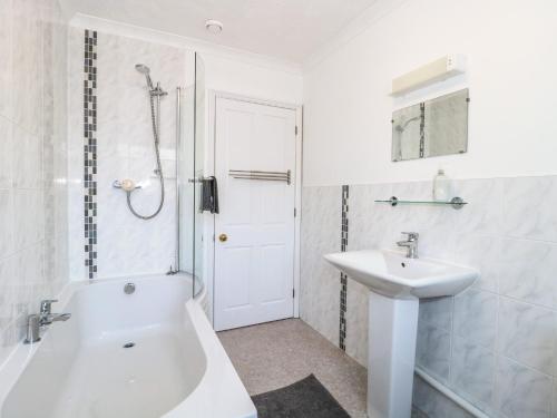a white bathroom with a sink and a tub and a shower at Quarry Cottage in Cheddar