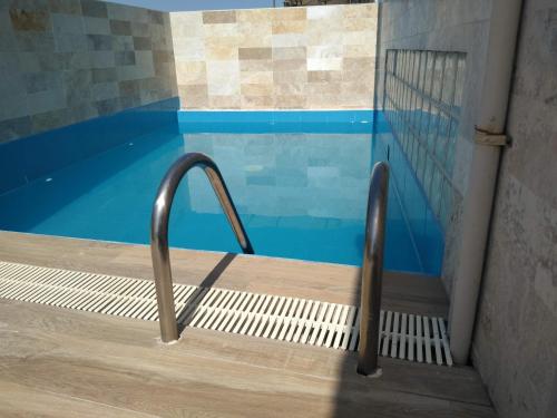 a swimming pool with a metal hand rail next to a door at Acogedor departamento WiFi in Piura