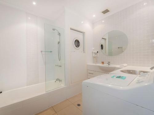 a white bathroom with a shower and a sink at 23 Sunseeker in Sunshine Beach