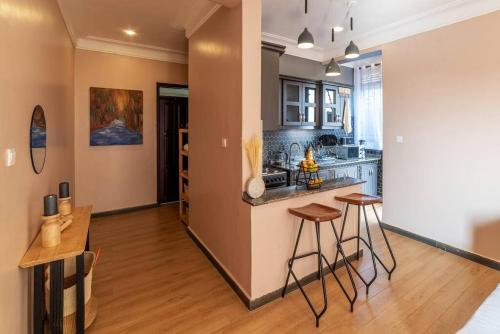 an open kitchen with a counter and stools at Mi Casa Su Casa - Kyanja in Kampala
