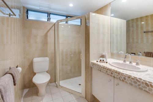 a bathroom with a shower and a toilet and a sink at Lagoon Beachfront Lodge 107 on Hamilton Island by HamoRent in Hamilton Island