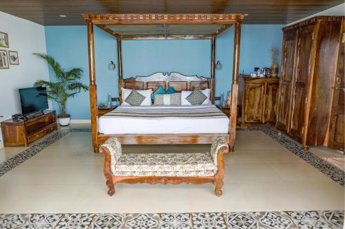 a bedroom with a canopy bed and a couch at The Cape Goa in Cabo de Rama