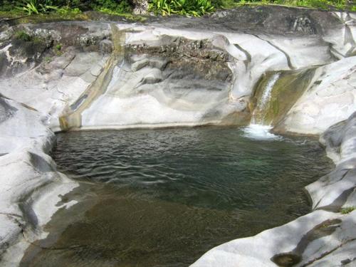 a pool of water next to a rock formation at CASAMELIAS "Le ficus" in Cilaos