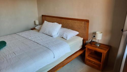 沙努爾的住宿－Agung's Annex Homestay，一间卧室配有白色床单和床头柜。