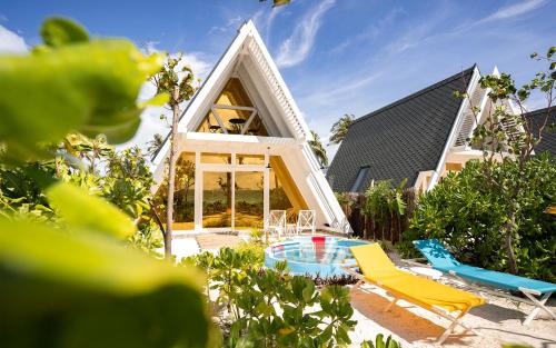 Oaga Art Resort Maldives - Greatest All Inclusive في نورث ماليه آتول: حديقة خلفية بها كرسيين ومنزل