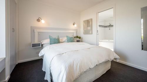 1 dormitorio blanco con 1 cama blanca grande con almohadas azules en Sunshine Retreat Villa 4, en Cowes