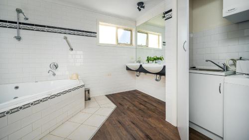 uma casa de banho com 2 lavatórios, uma banheira e um lavatório. em Sunshine Retreat Villa 6 em Cowes