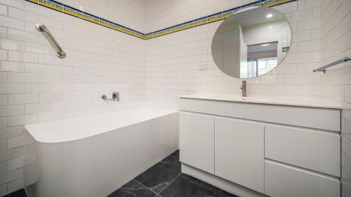 een witte badkamer met een bad en een spiegel bij Sunshine Retreat Villa 7 in Cowes