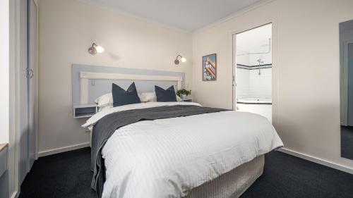 a white bedroom with a large bed with blue pillows at Sunshine Retreat Villa 1 in Cowes