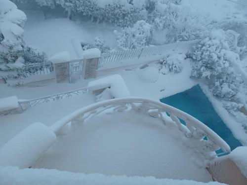 a snow covered garden with a bridge and a pond at Apartment with a garden, BBQ, swimming pool and jacuzzi in Drafí