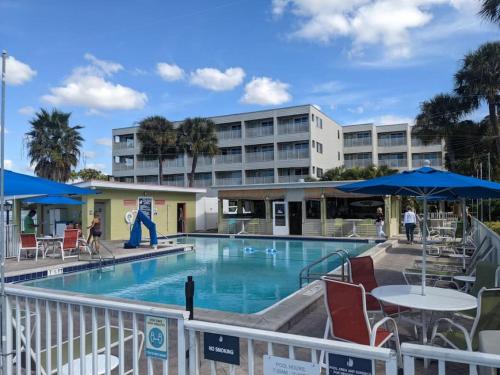 une piscine avec des chaises et des tables ainsi qu'un bâtiment dans l'établissement Tampa Bay Breeze Direct Bay View From Porch, à Tampa