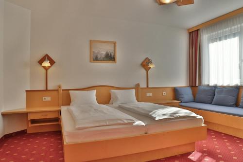 una camera con un letto e un divano blu di Pension Posauner a Dorfgastein