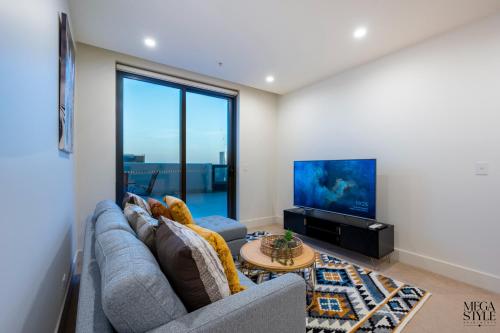 a living room with a couch and a tv at Mega Style Apartments Vision in Melbourne