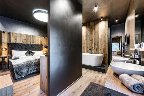 a bathroom with a bed and a tub and a sink at ALMMONTE PRÄCLARUM SUITES Design Hotel in Wagrain