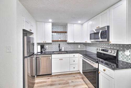 a kitchen with white cabinets and stainless steel appliances at Fantastic Boho Chic Home Clearwater St Pete Tampa in Largo