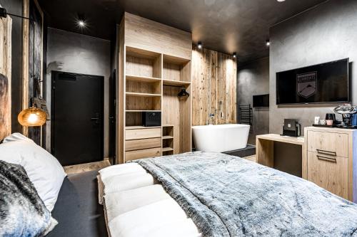 a bedroom with a bed and a tub and a sink at ALMMONTE PRÄCLARUM SUITES Design Hotel in Wagrain